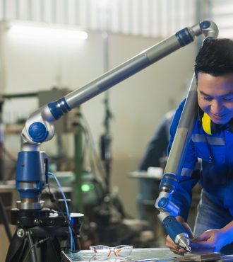 asian male engineer specialist with Measuring machine with a manipulator arm.Three-dimensional coordinate measurement. Check sizes. 3D check of the sizes of parts. CMM after machining process